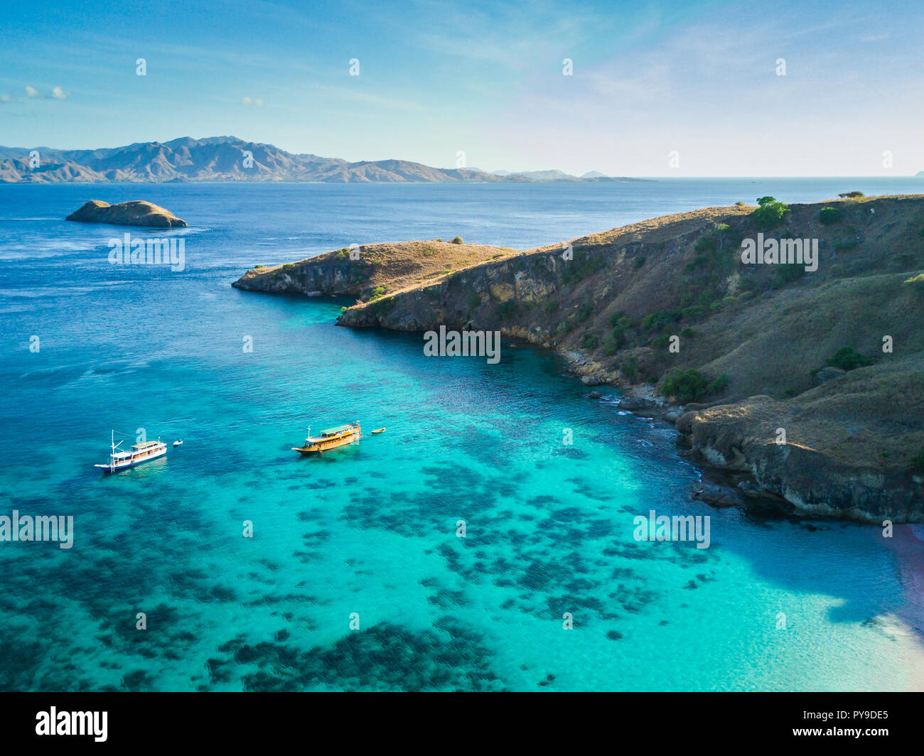 Drone shot of 2 boats anchored on the coast of Pulau Padar, Indonesia, right in front of Pink Beach Stock Photo