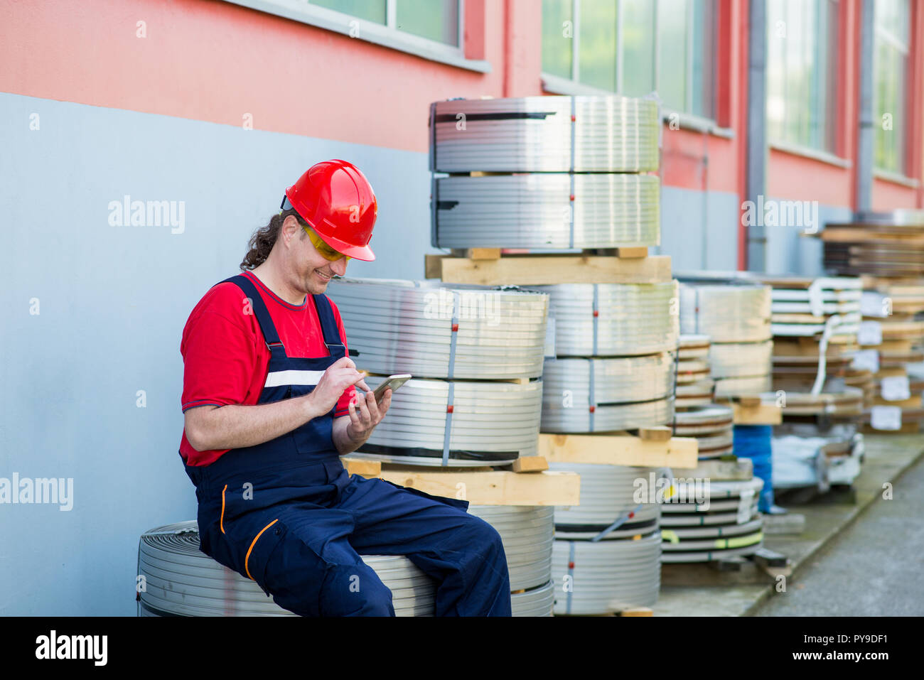 Worker using his mobile phone and relaxing outside a factory Stock ...