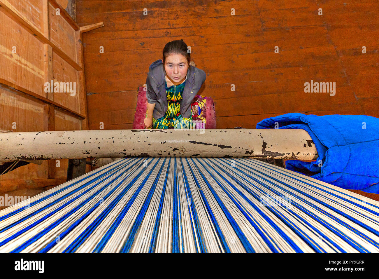 Local girl weaving rug and looking up the weaving loom, in Nukus, Uzbekistan Stock Photo