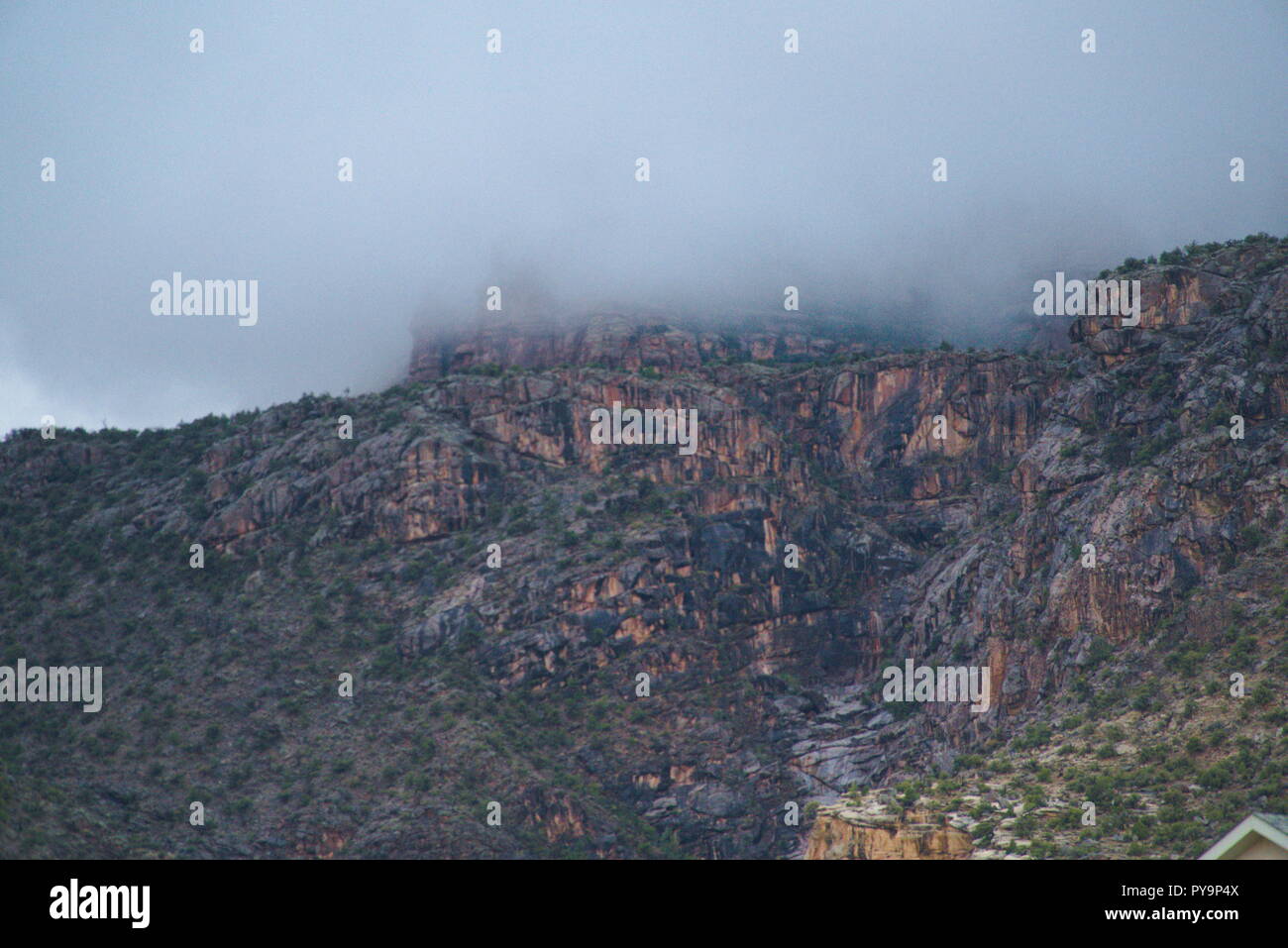 The Colorado National Monument shrouded by a layer of heavy fog. The clouds above are grey and gloomy. There is an overall downcast vibe. Stock Photo