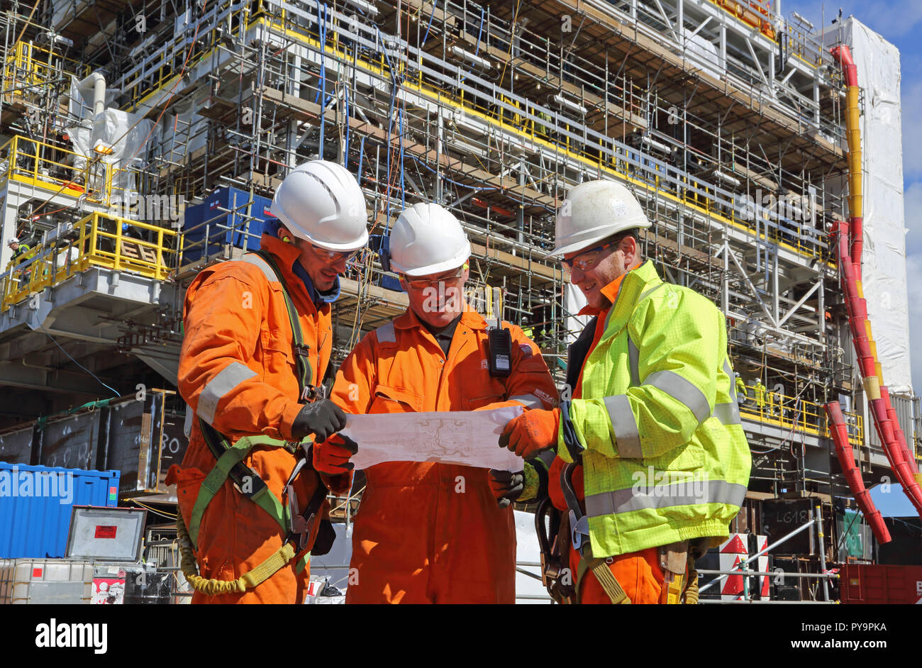 3 engineers discus a drawing during the construction of an offshore gas production platform in the North Sea port of Hartlepool, UK Stock Photo