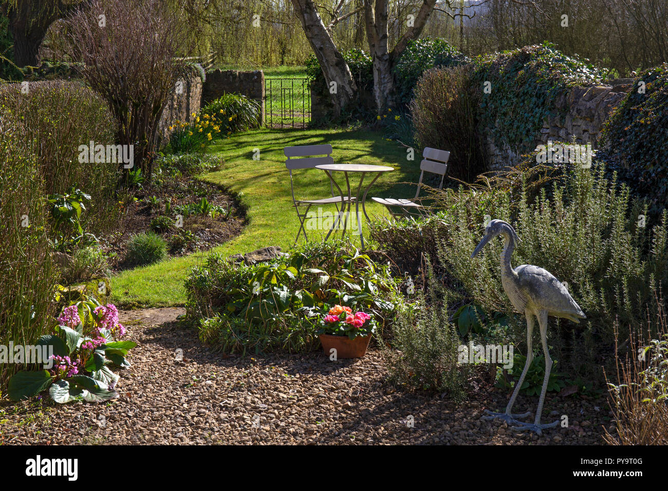 Spring garden with outdoor seating and heron statue leading unto gateway in English Garden,England,Europe Stock Photo