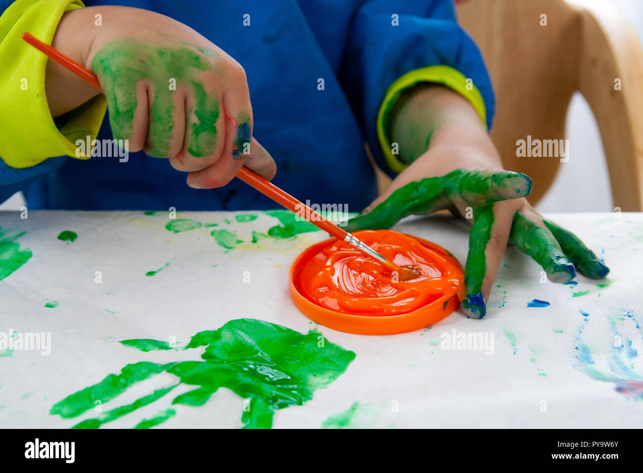 Child painting with finger paint and a brush Stock Photo