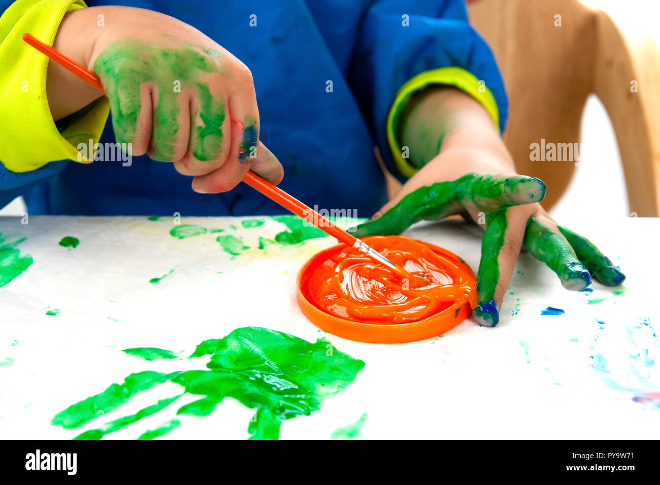 Child painting with finger paint and a brush Stock Photo