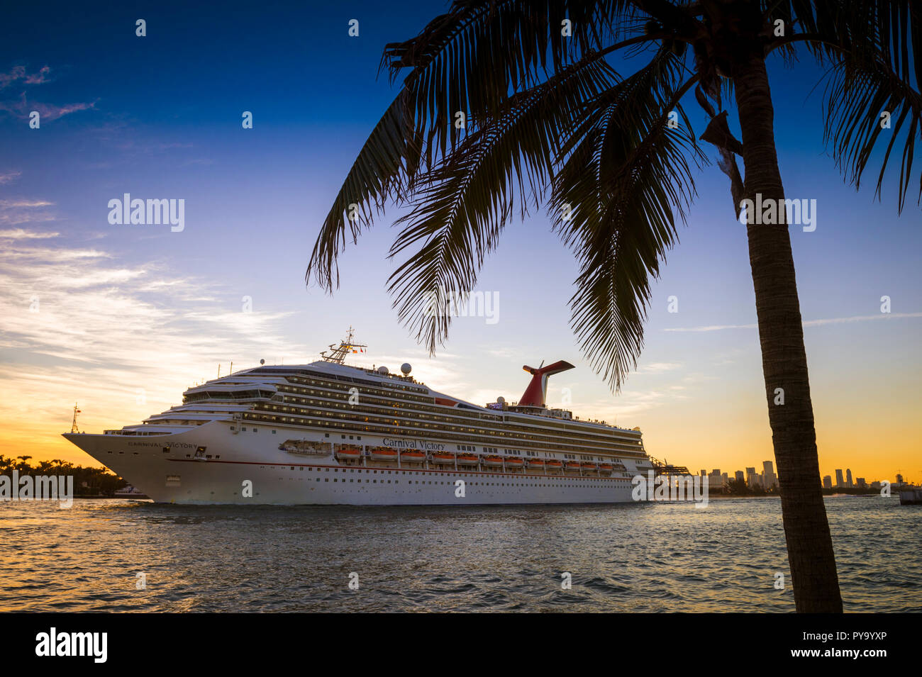 MIAMI - CIRCA AUGUST, 2018: The Carnival Victory Cruise ship passes in front of the city skyline during a sunset departure. Stock Photo