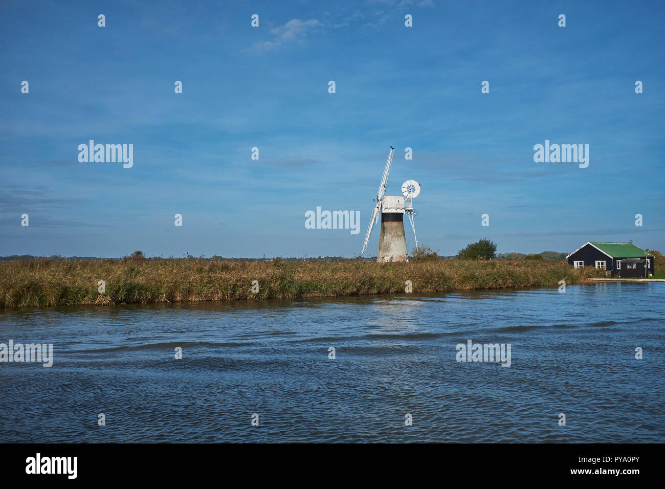 A disused windmill next to the River Thurne on a clear autumn day Norfolk Broads, Norfolk, England, UK Stock Photo