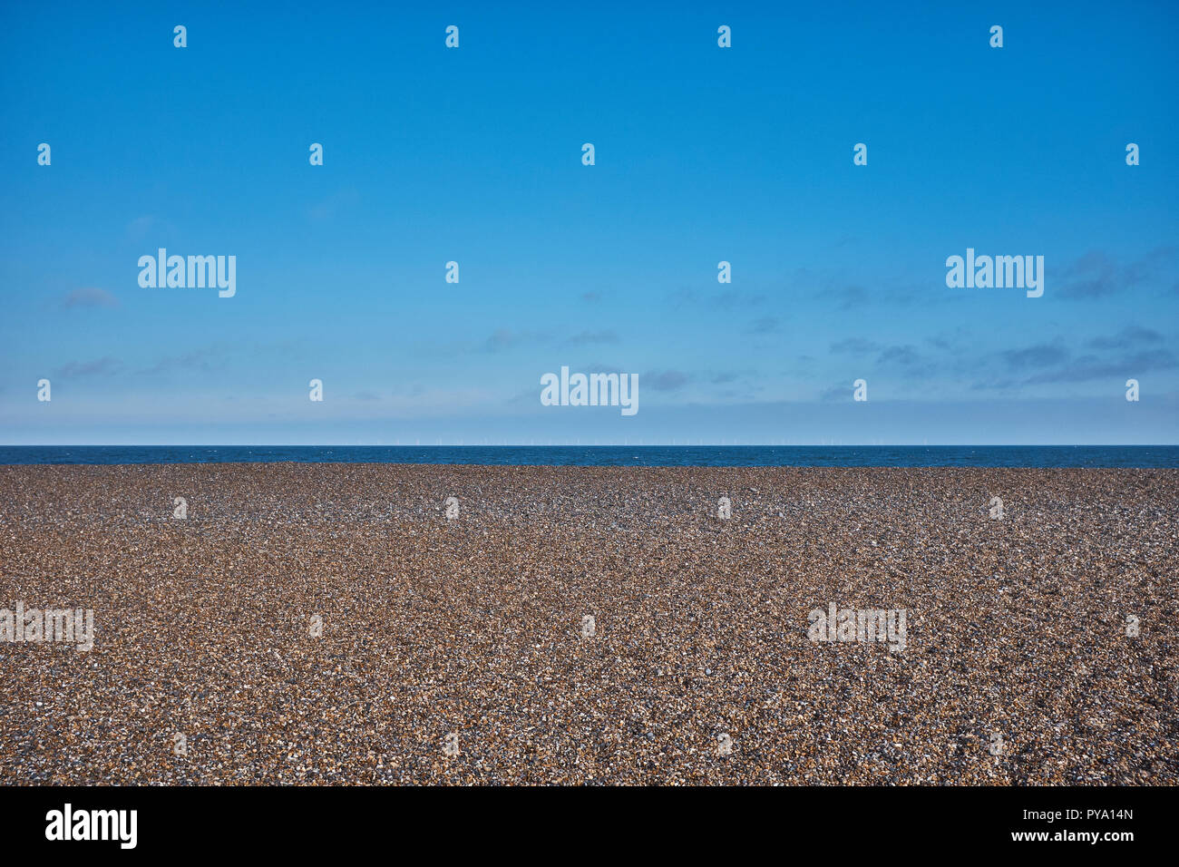 Pebble beach with no people at Clay On Sea with large amount of blue sky and small amount of sea Stock Photo