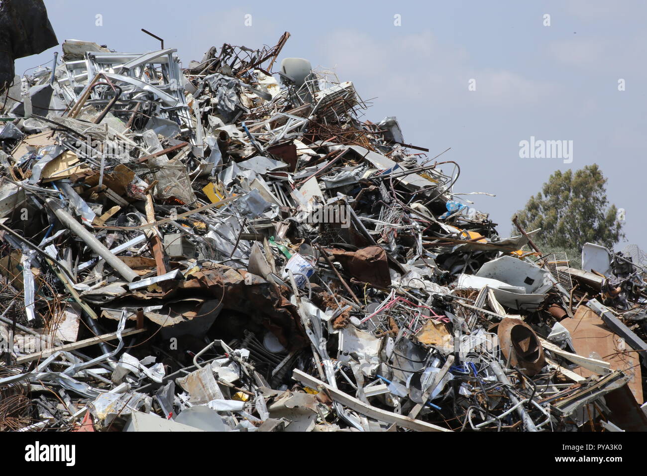 Metal waste, metal Recycling. Pile of metal waste, Metal Recycling with a tree in the background. Stock Photo