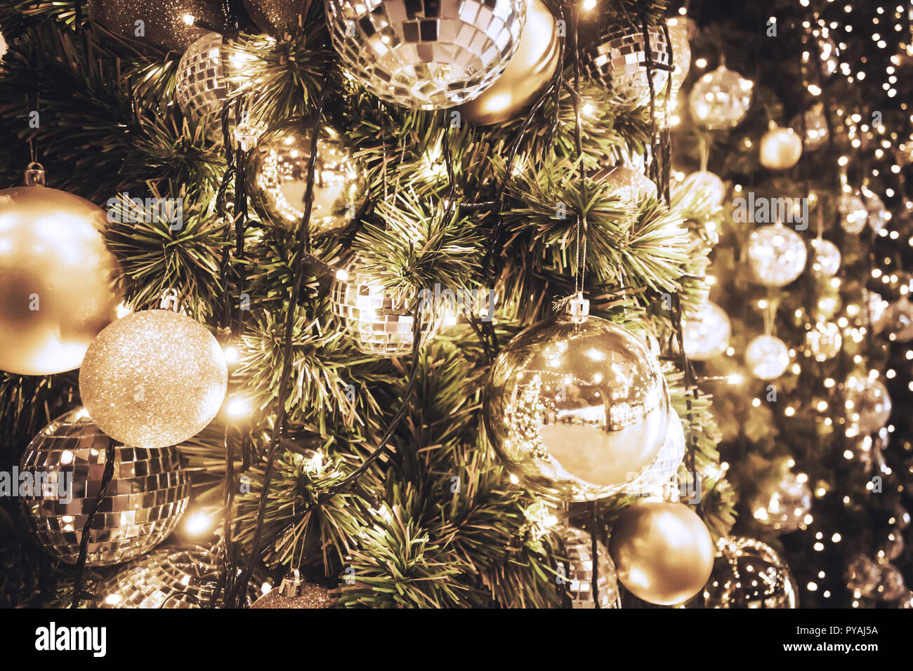 Christmas tree with gold ball and bokeh lights background. Xmas abstract close up with glowing decorations outdoors. Stock Photo