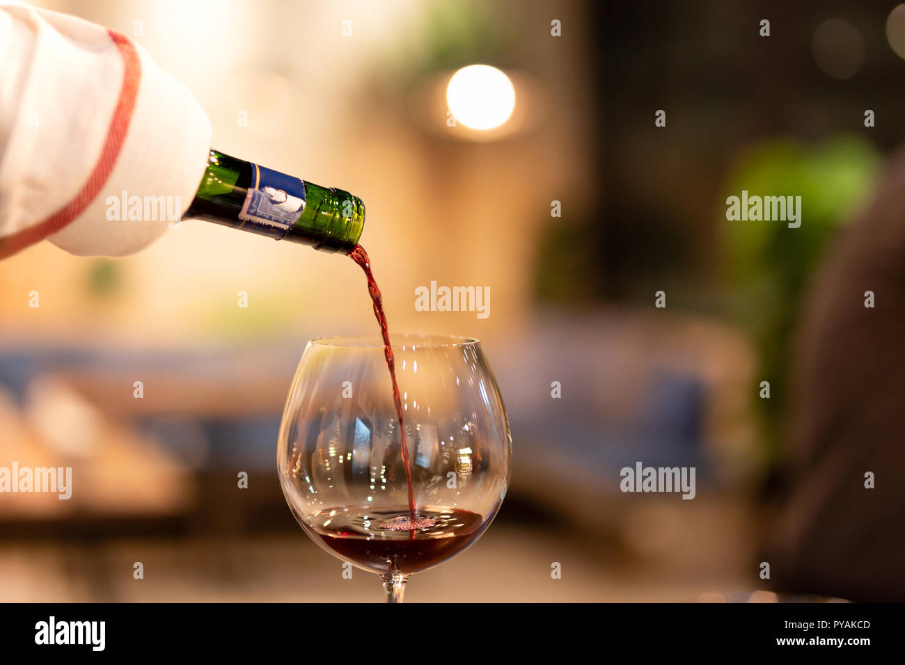 Shot in low light and high iso red wine pouring down from wine bottle. Stock Photo