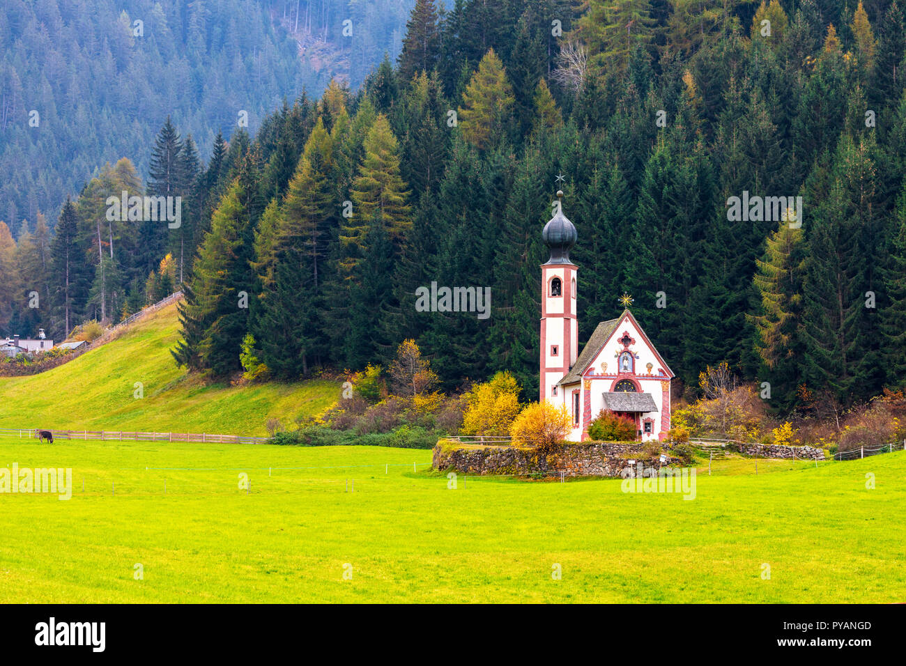 Small church located in a meadow with high mountain peaks behind Stock Photo