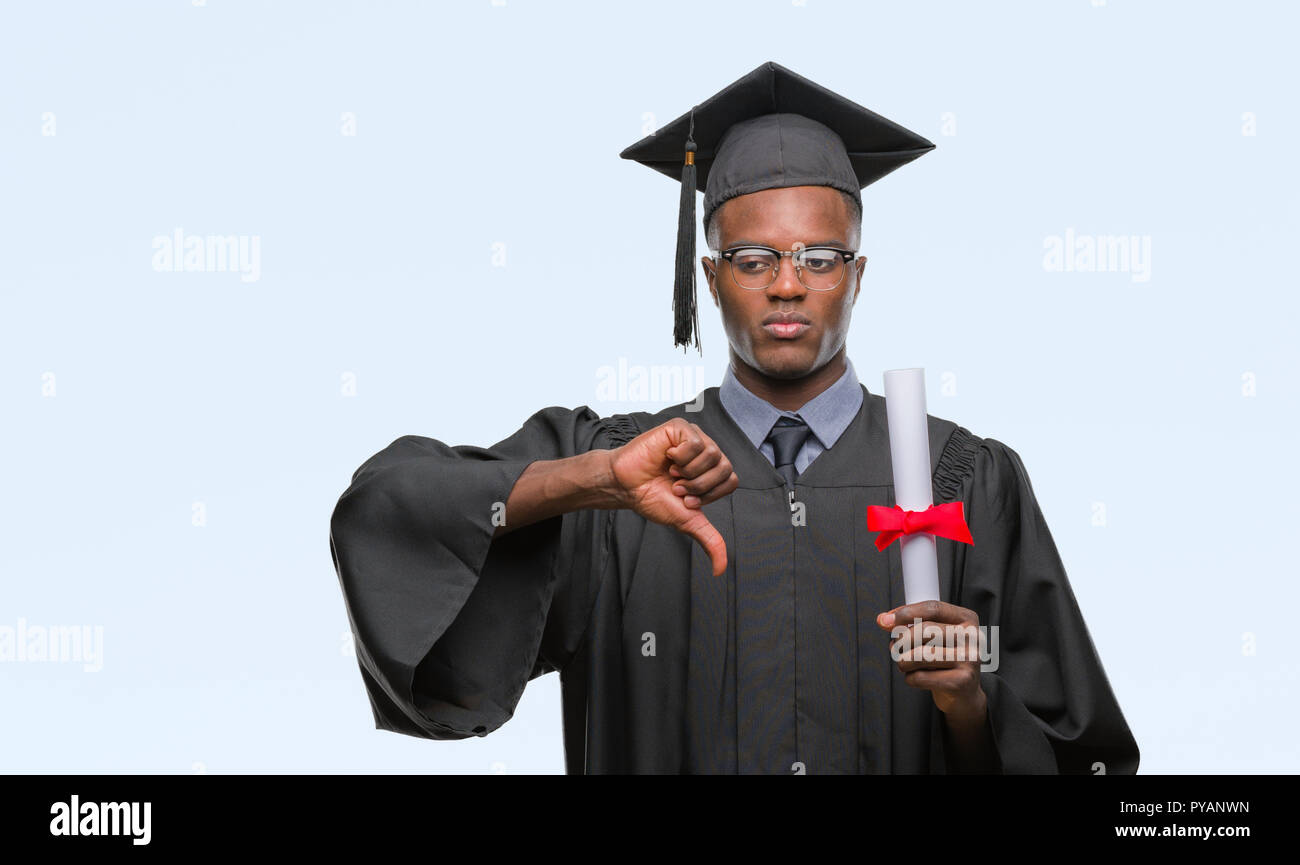 Young graduated african american man holding degree over isolated background with angry face, negative sign showing dislike with thumbs down, rejectio Stock Photo