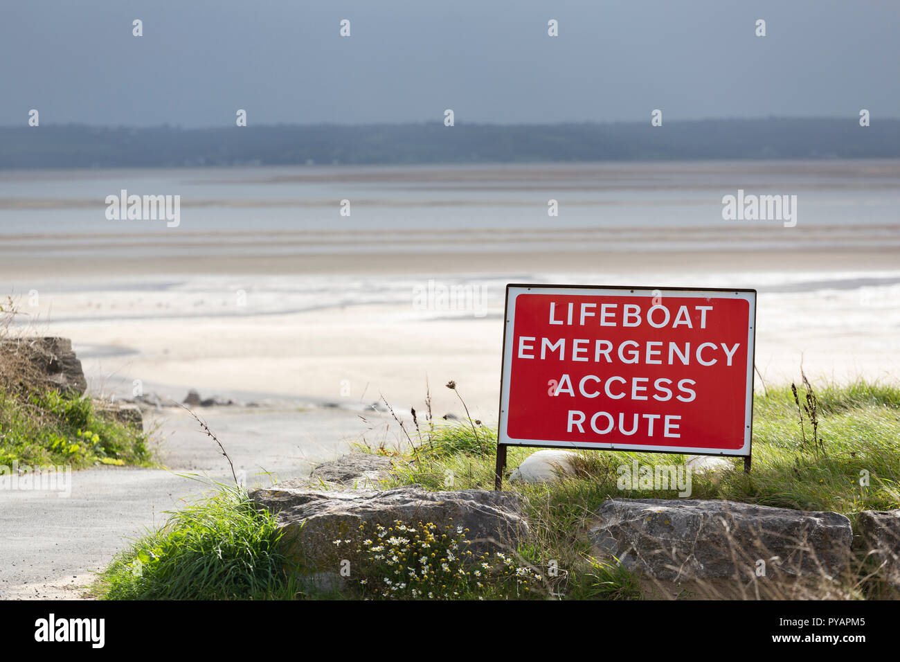 Sign saying Lifeboat Emergency Access Route near slipway into sea Stock Photo