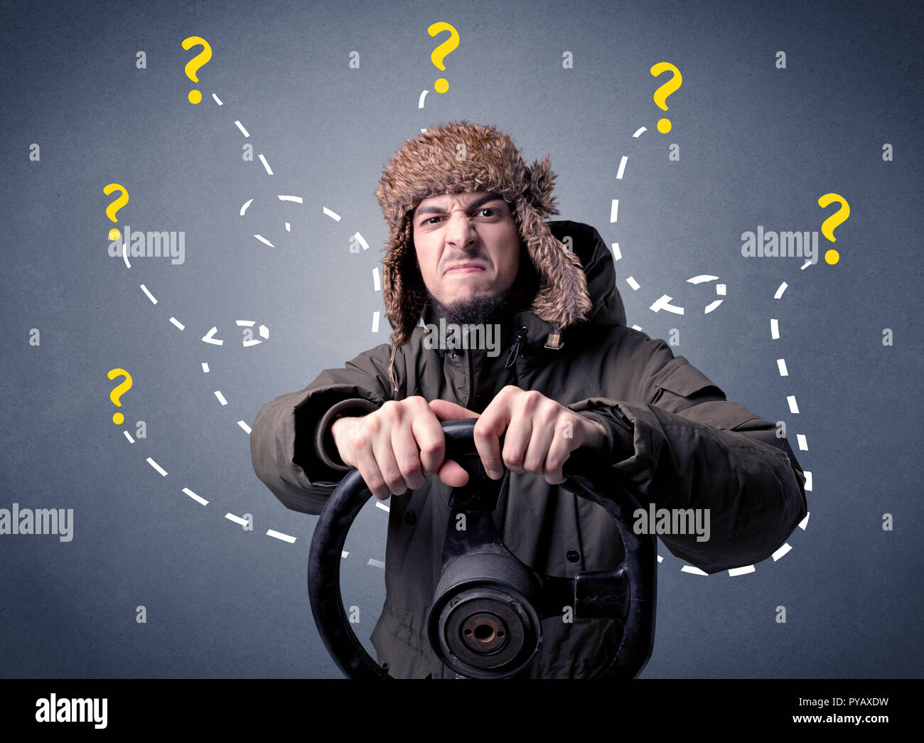 Young man holding black steering wheel with question marks around him