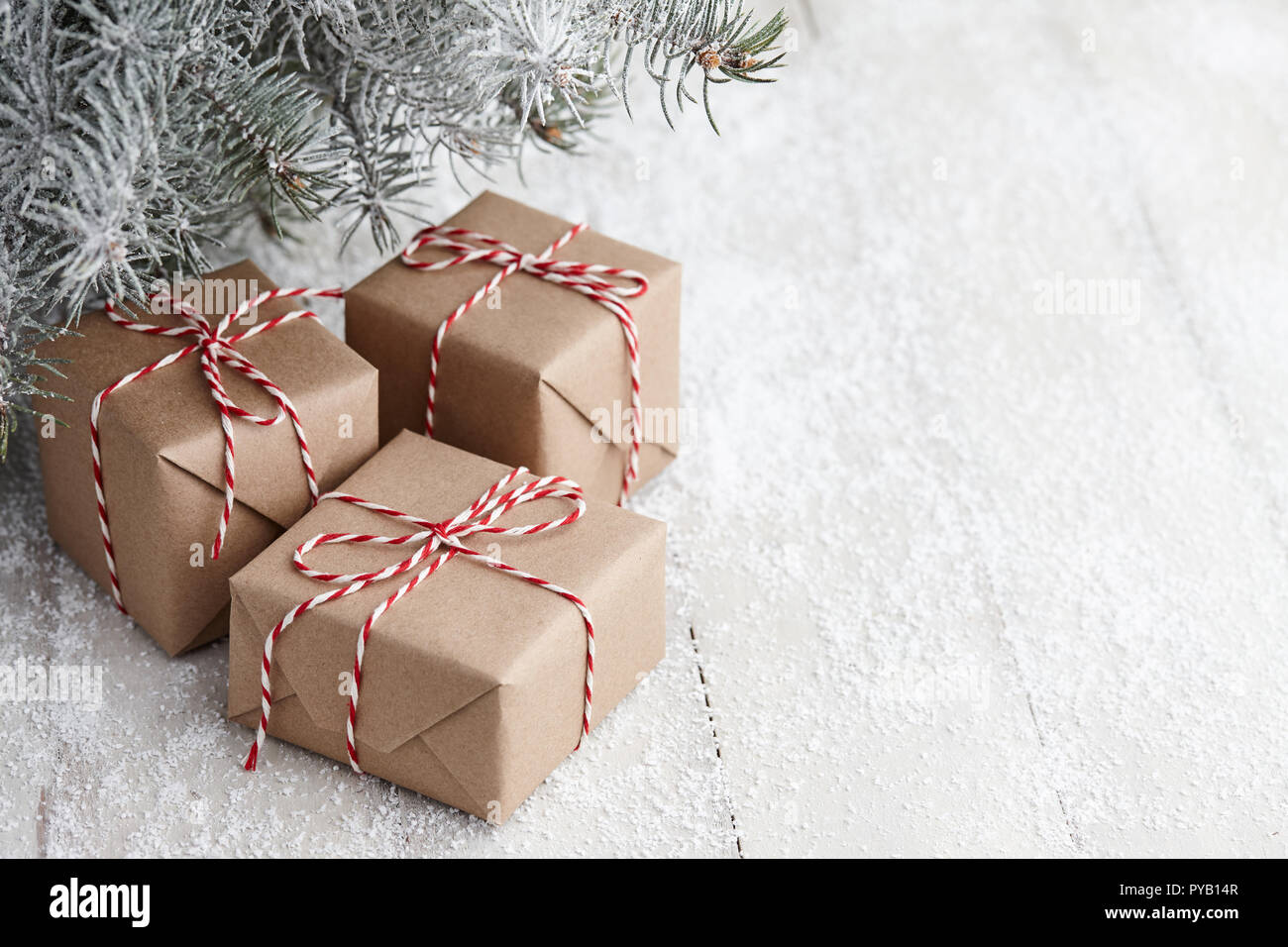 Christmas gift boxes wrapped in kraft paper under snowy fir tree ...
