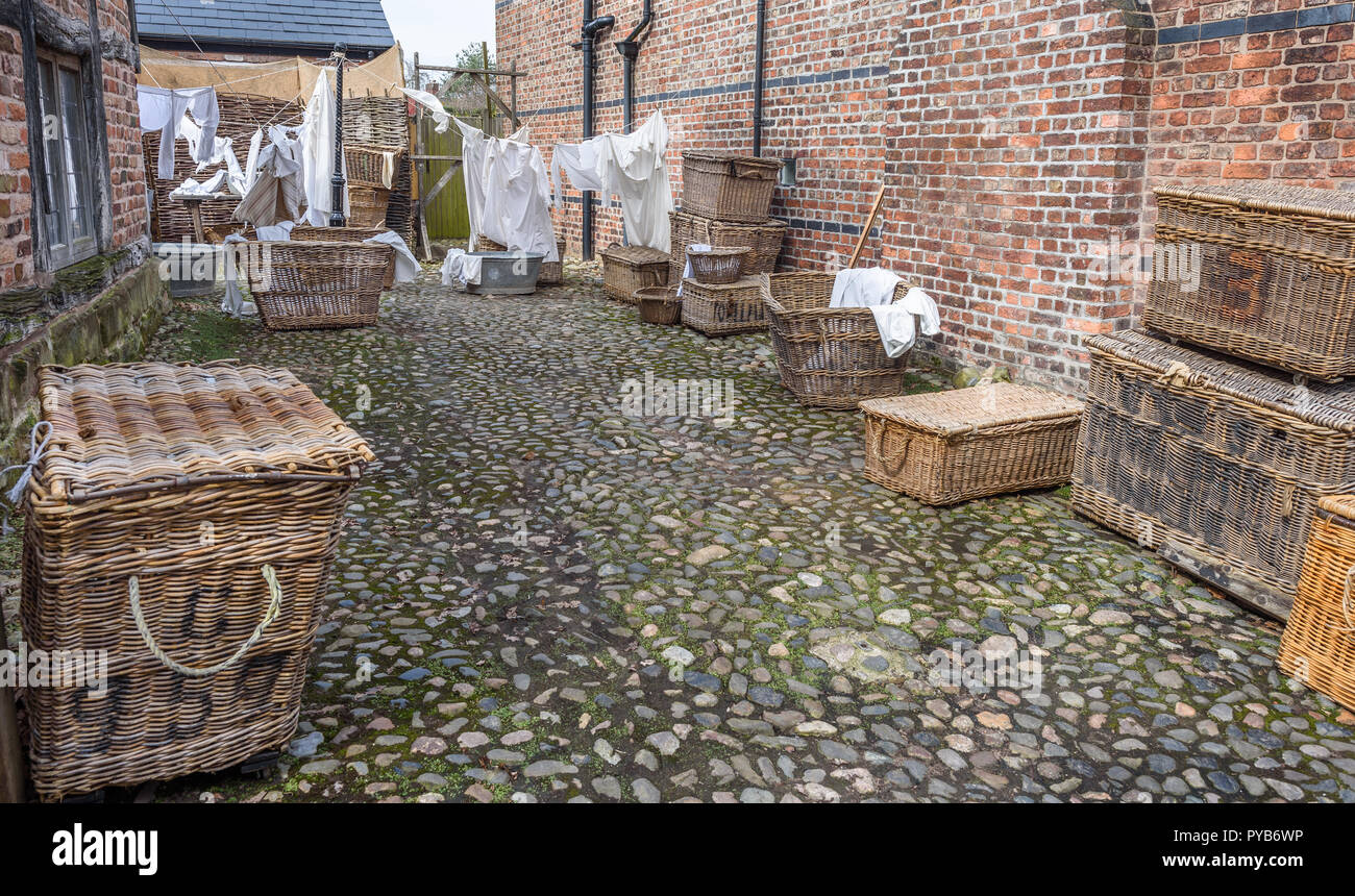 Old fashioned washing baskets and laundry drying on a line in a cobbled yard. Stock Photo