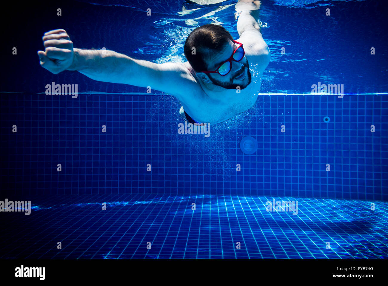 young man with sunglasses enjoying the swimming pool abstract summer fun underwater swimming jump diving background Stock Photo