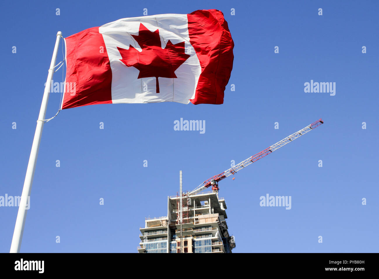 Canadian Flag Waving Over Crane And Building On Construction Site