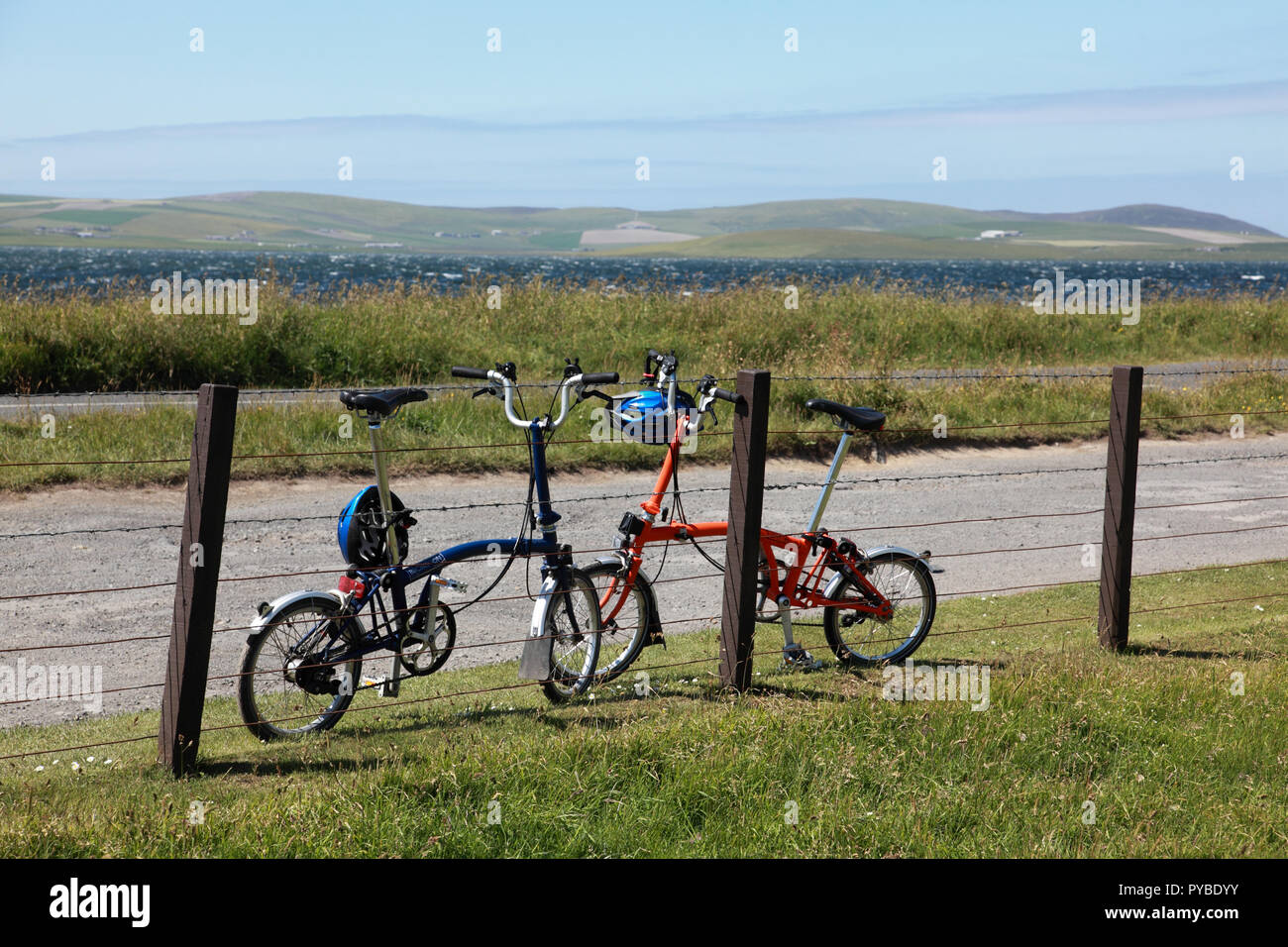 Fold up bicycyles parked against a fence while their riders visit the Standing Stones of Stenness, on Orkney, Scotland Stock Photo