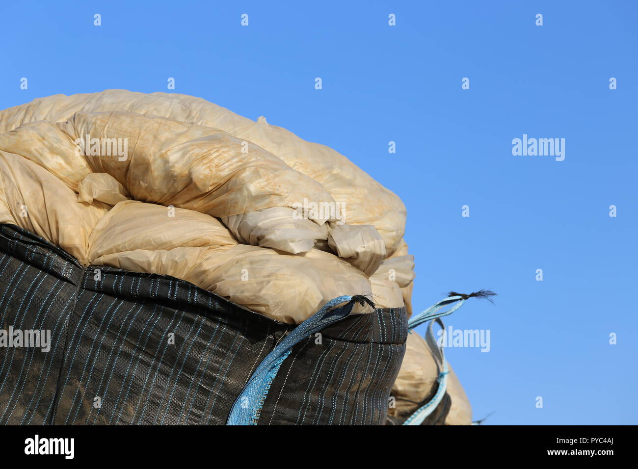 Plastic Sheets in a Nylon Sack. Dirdy Plastic sheets in a huge black bulk bag, close up. Agricultural plastic usage. Stock Photo