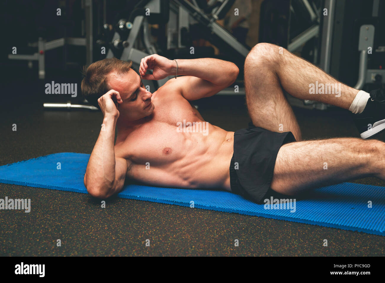 Muscular man on floor working out on abdominal muscles. Stock Photo