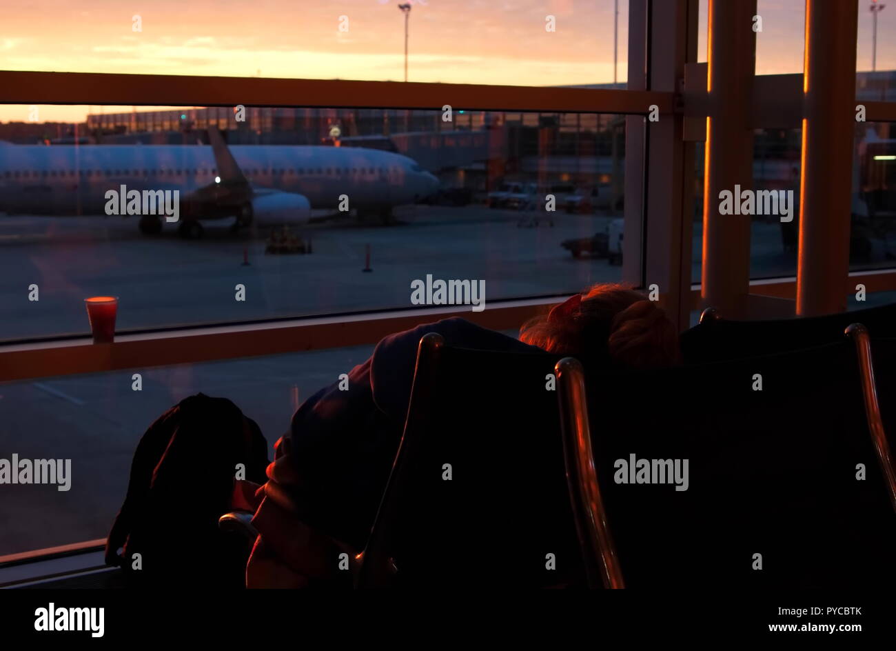 Washington DC, Reagan National Airport, Aug 2015. A sleeping passenger at the airport gets a little warmth from the morning sunshine. Stock Photo