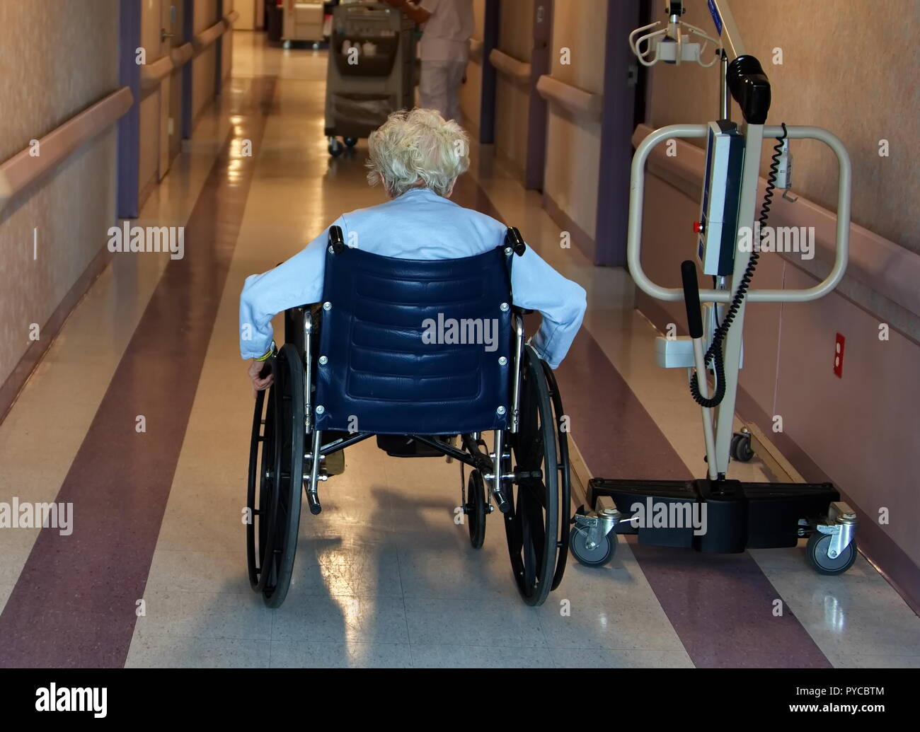 New York City, NY USA. Feb 2016. An elderly woman in a wheel chair traveling down a nursing home corridor. Stock Photo