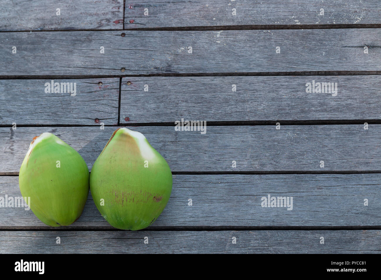 Green coconuts on a wooden floor Stock Photo