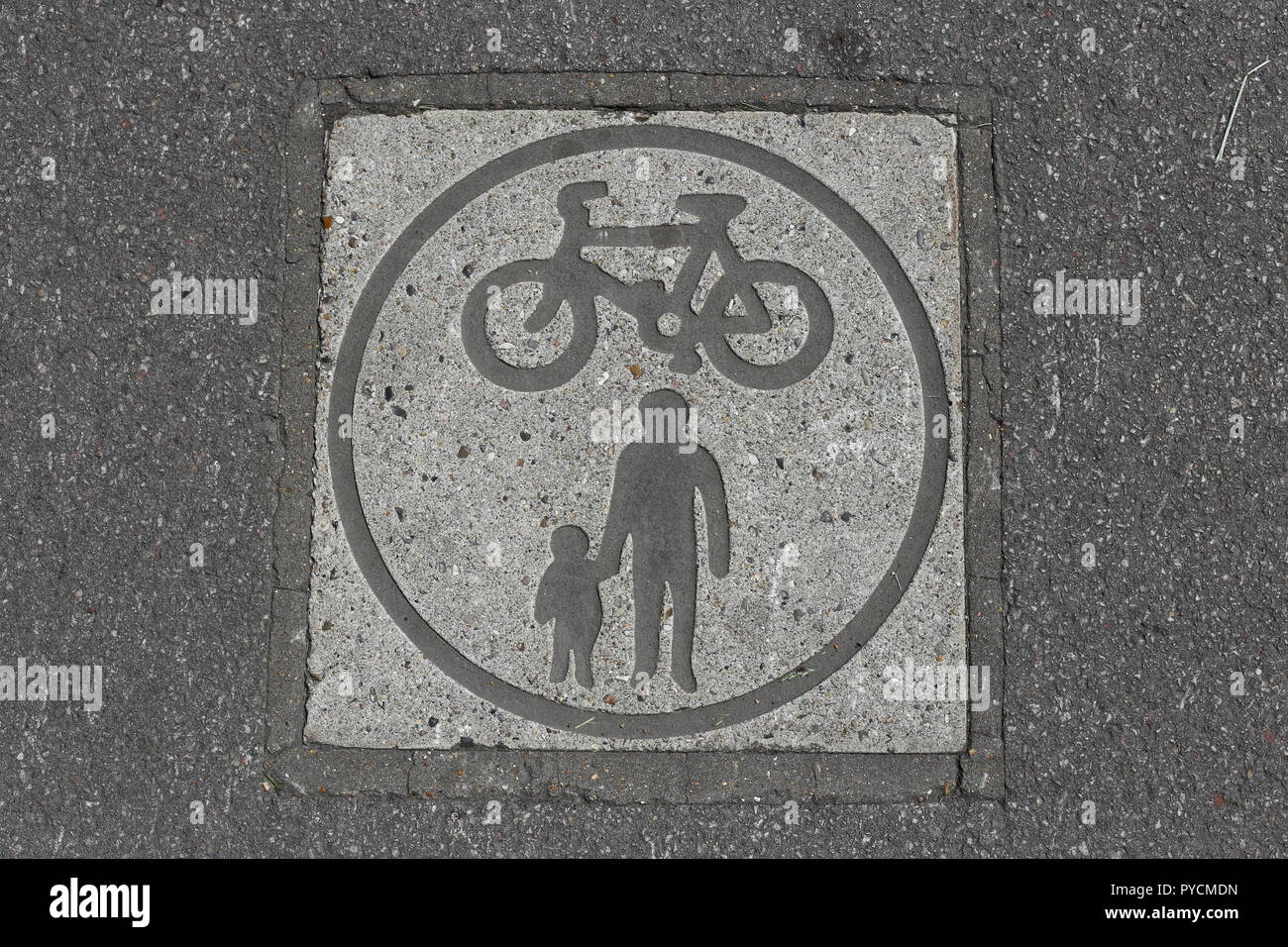 Path Sign For Cycling And Pedestrians.  A signal embedded in asphalt marking a bike and pedestrian route in the park. Stock Photo