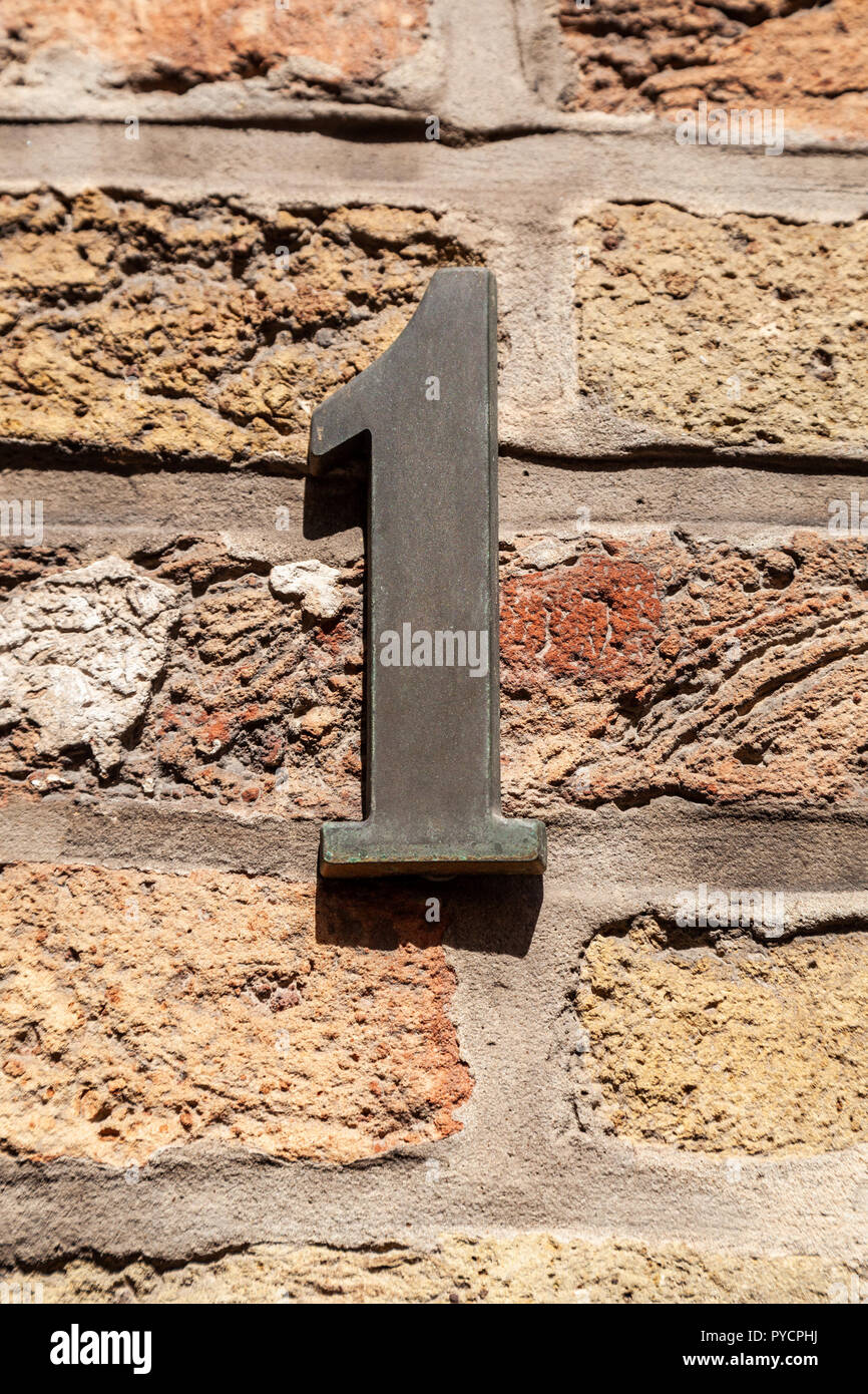 House number one 1 in designer font in cast polished metal, brass looking weathered or tarnished from Sweden Stock Photo