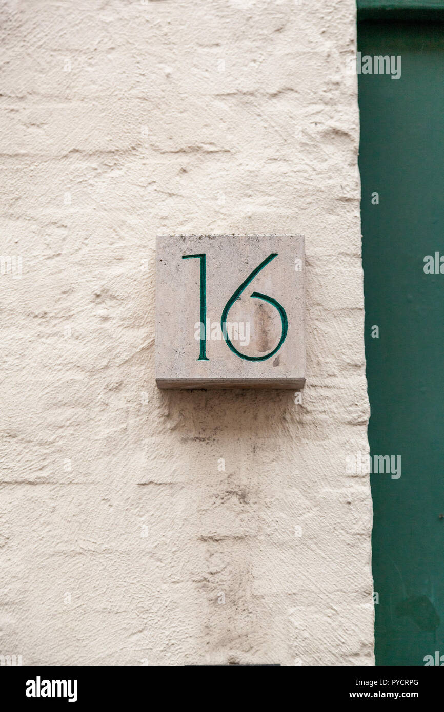 House number sixteen 16 painted green carved in white stone glued to bricks in Sweden Stock Photo