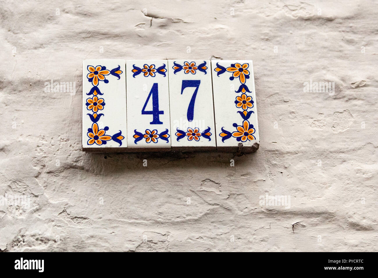 House number forty-seven 47 painted on ceramic tile in blue and yellow, red and gold from Sweden Stock Photo