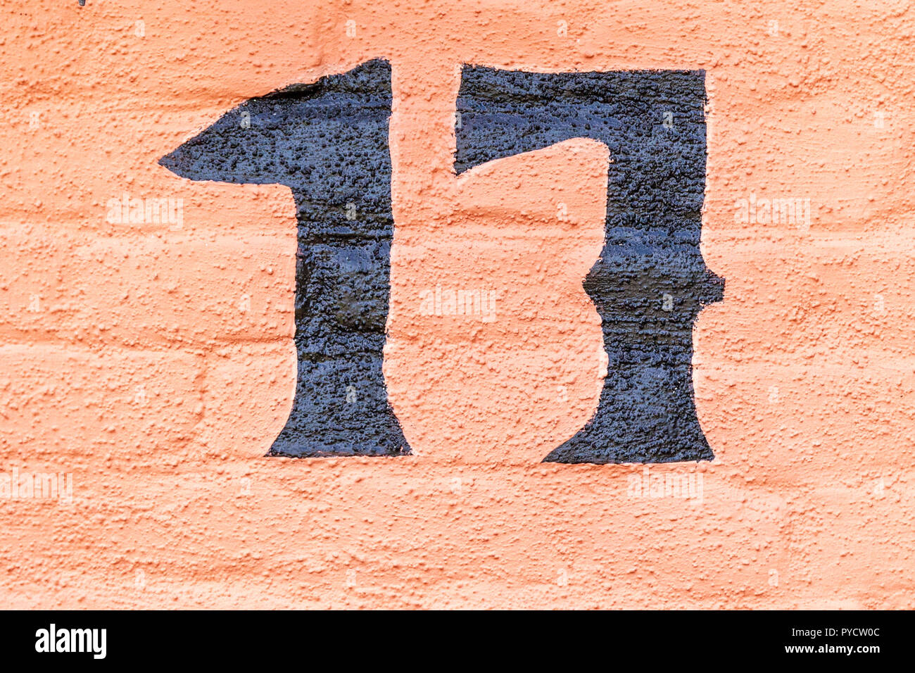 House number seventeen 17 painted in black paint on an orange background on brick from Sweden Stock Photo