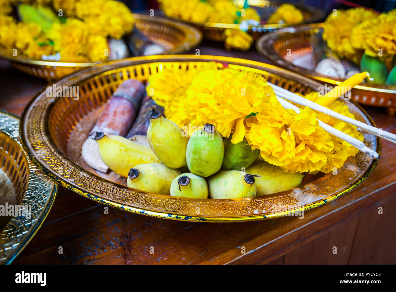 Buddhist offerings of flowers, incense, banana and rice on a plate in the temple, close up