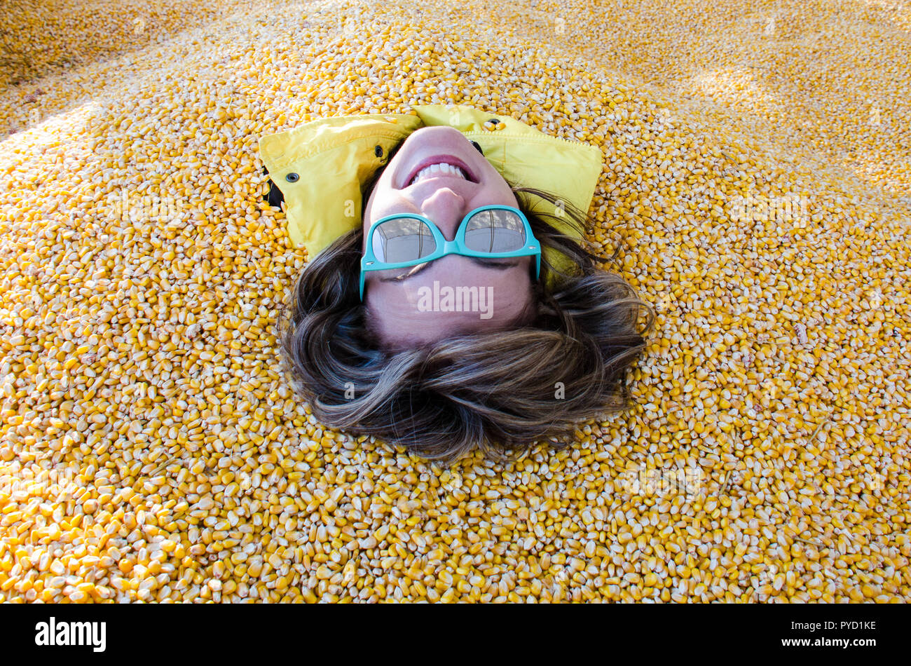 An adult female has her entire body covered and buried in corn kernels