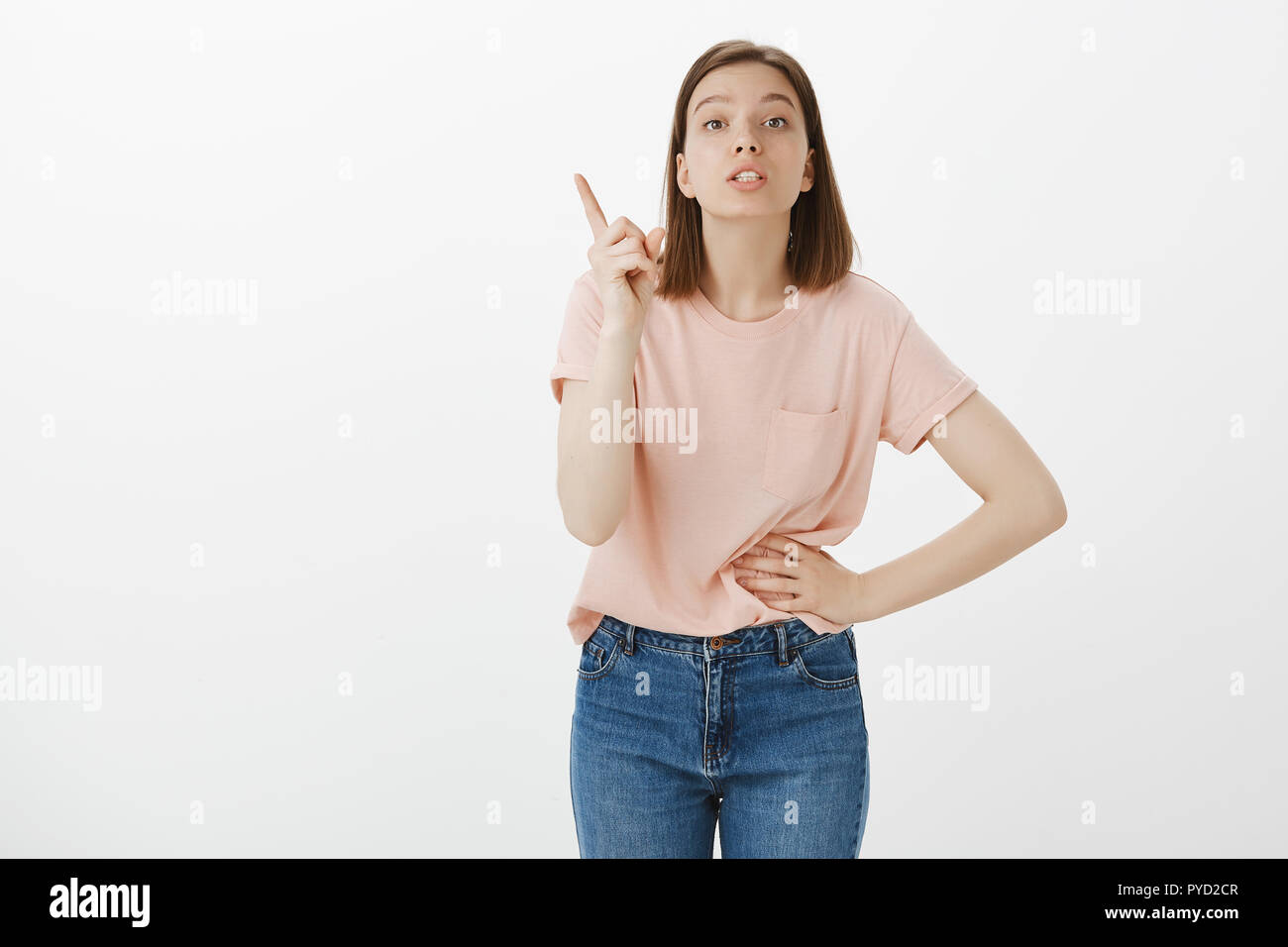 Girl scolds brother, giving directions. Attractive smart smart woman holding hand on waist and shaking index finger while shame sibling for bad behaviour, posing over gray background Stock Photo