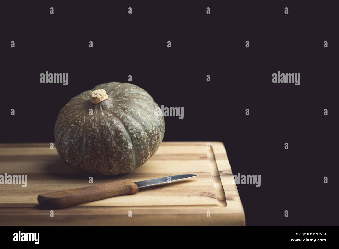 Pumpkin and knife on a wooden cutting board Stock Photo