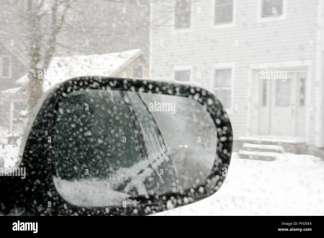 A snowy road as seen through the rear view mirror of a car Stock Photo