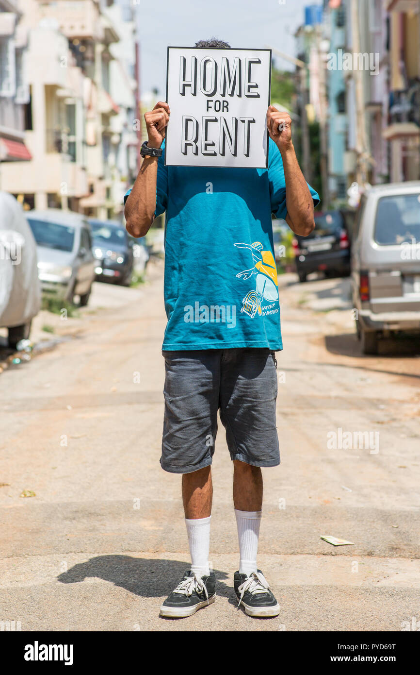Man standing on a road with a sign saying 'home for rent' Stock Photo