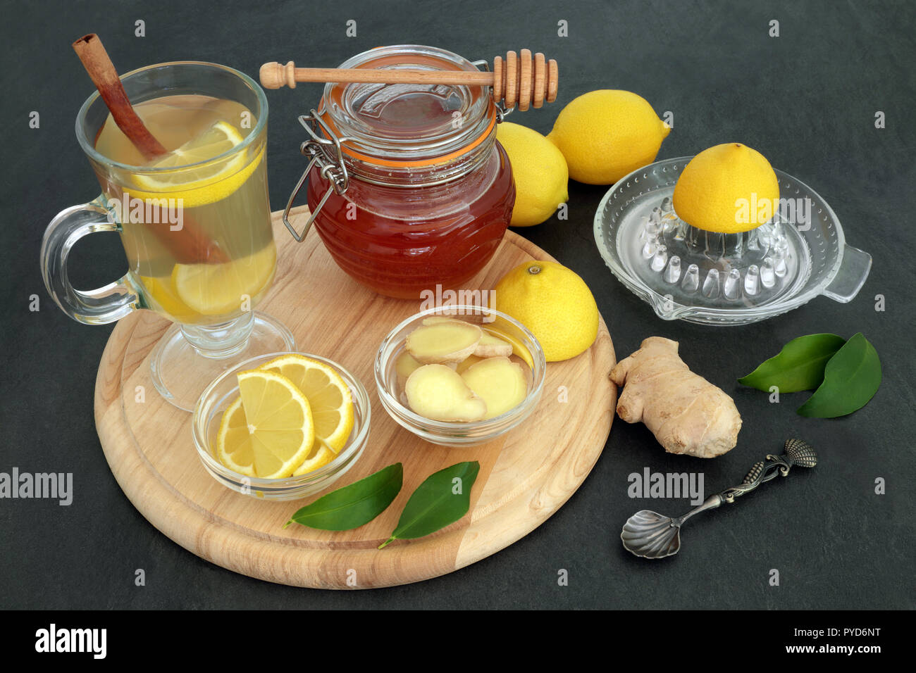 Natural flu and cold remedy ingredients with fresh ginger, lemon fruit, cinnamon sticks and honey with natural medicinal hot drink on slate background Stock Photo