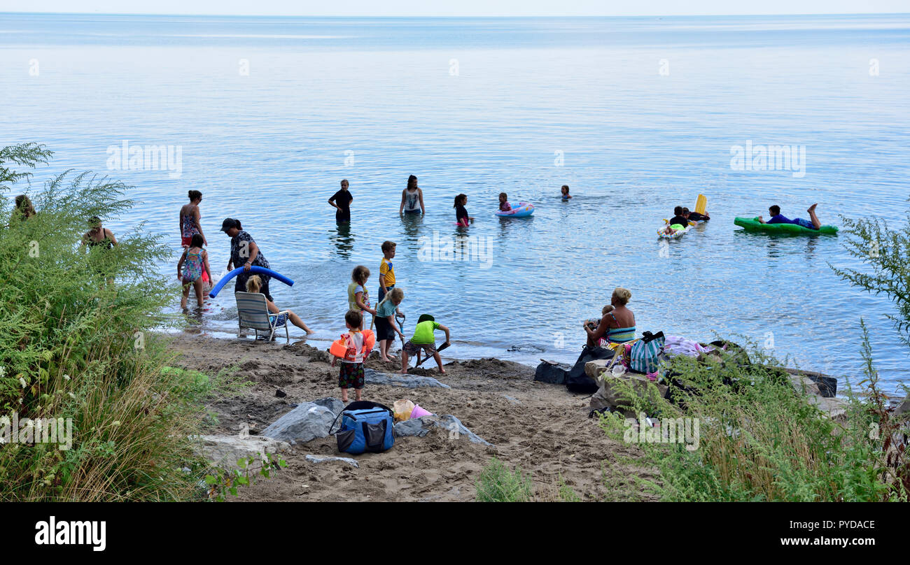 People playing on small beach and in water of  Lake Ontario, New York State, USA Stock Photo