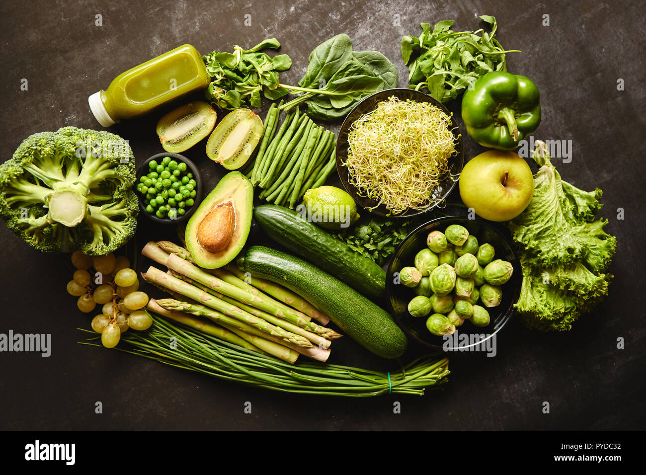 Green healthy food composition with avocado, broccoli, apple smoothie, cucomber, asparagus, kiwi and bean. Placed on dark background. Top view. Stock Photo