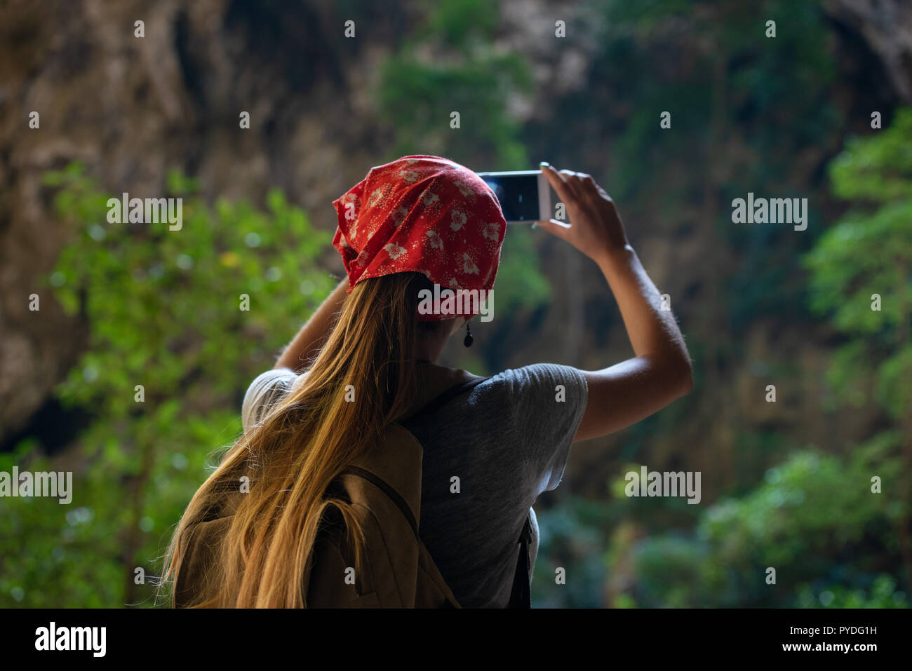 Girl tourist makes mobile photo by phone in tropical cave Stock Photo