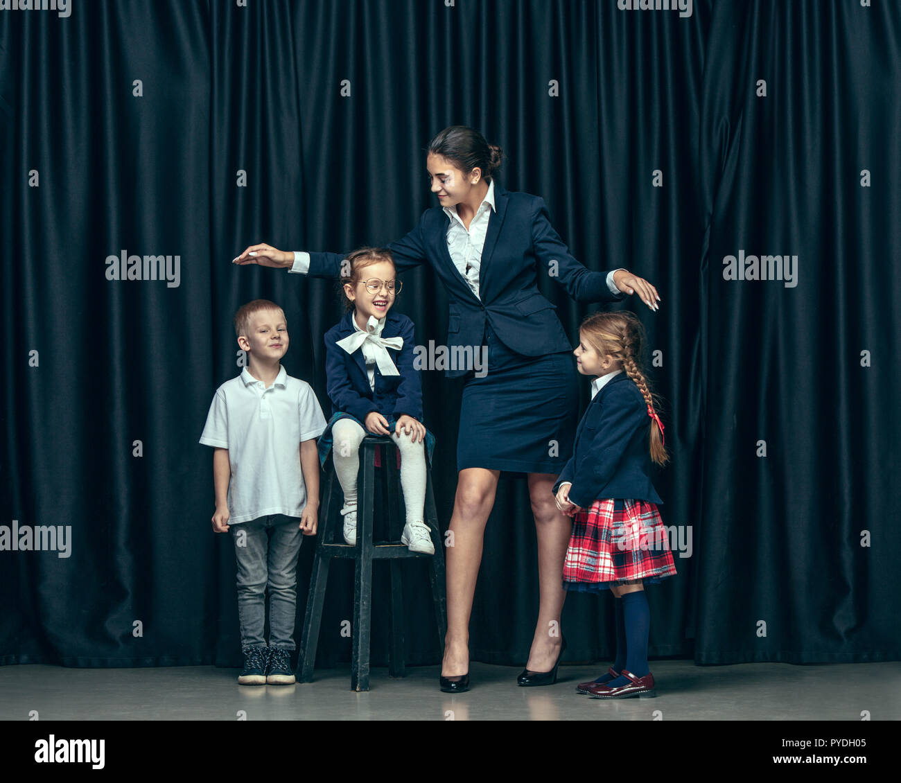 Cute smiling happy stylish children and female teacher on dark ...