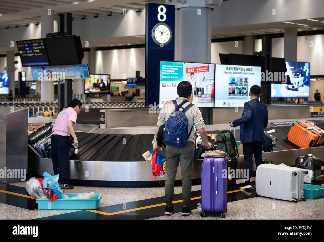 Travellers are seen waiting for their luggages at their assigned pick