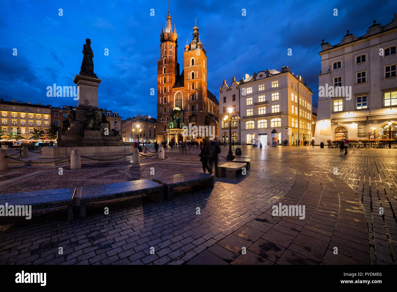 Main Square in the Old Town of Krakow city in Poland, Adam Mickiewicz monument and St. Mary Basilica at dusk. Stock Photo