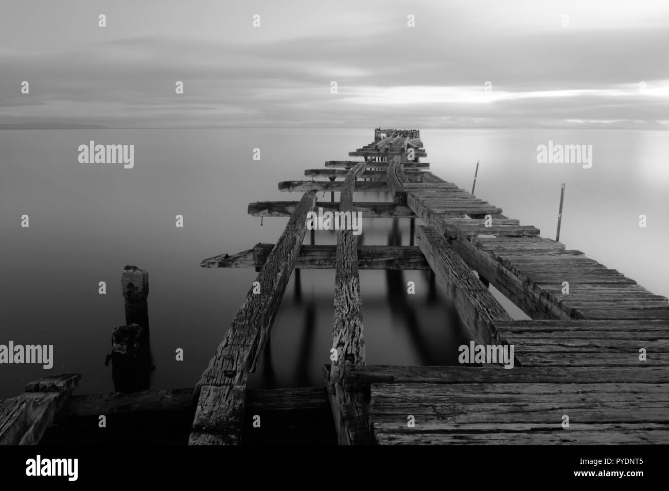 Old broken down wooden pier in Punta Arenas, old dock in Chile on the Pacific ocean. sunset Stock Photo