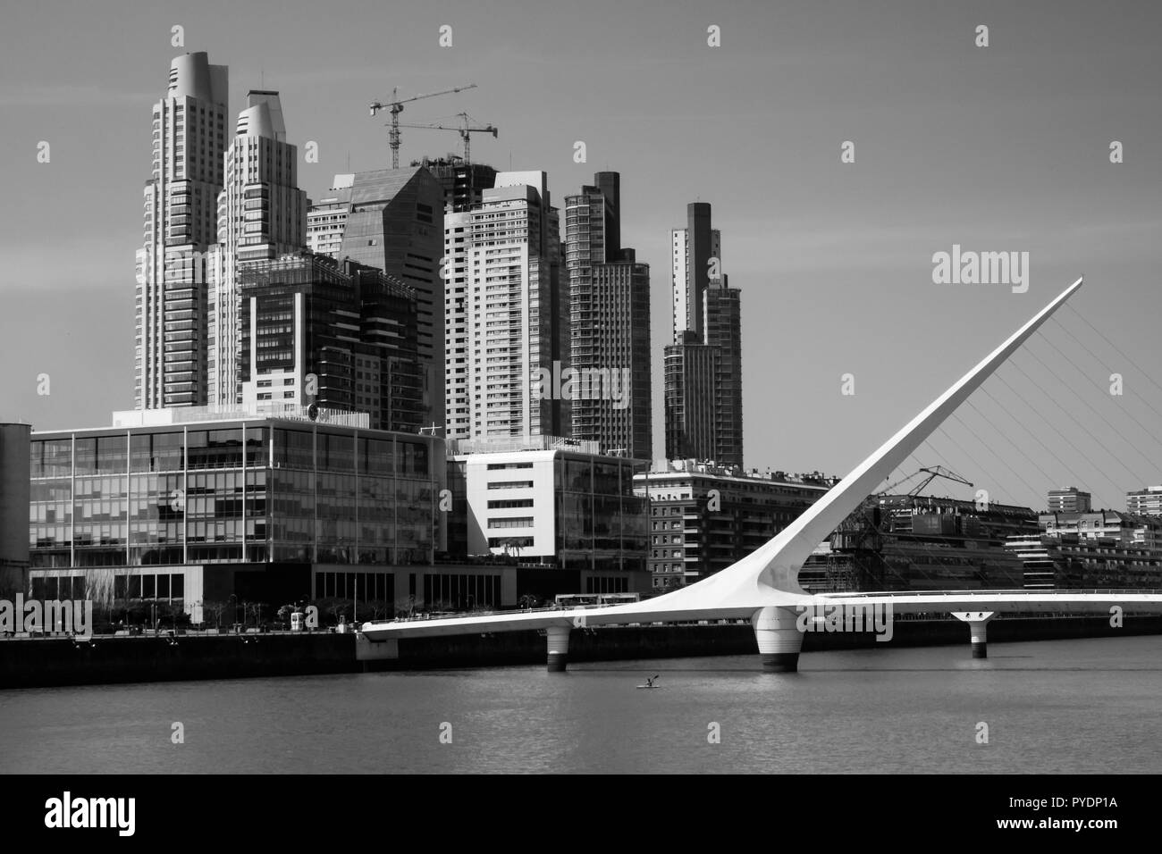 Woman Bridge of Calatraba in Buenos Aires. Puerto Madero. Black and White buildings, river and man doing kayak Stock Photo