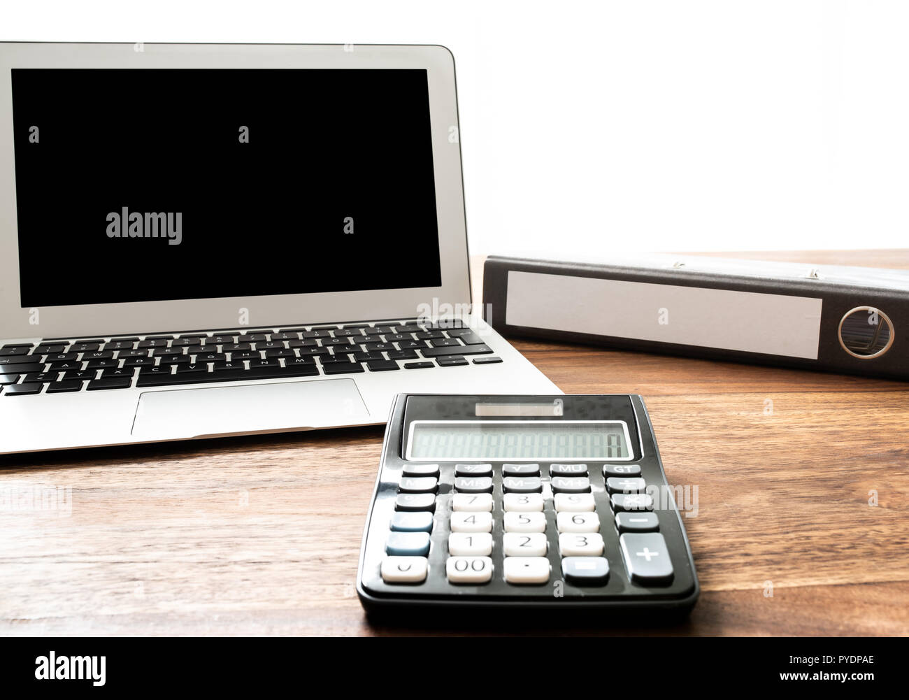 low angle view of calculator, laptop and file folder on wooden desk Stock Photo