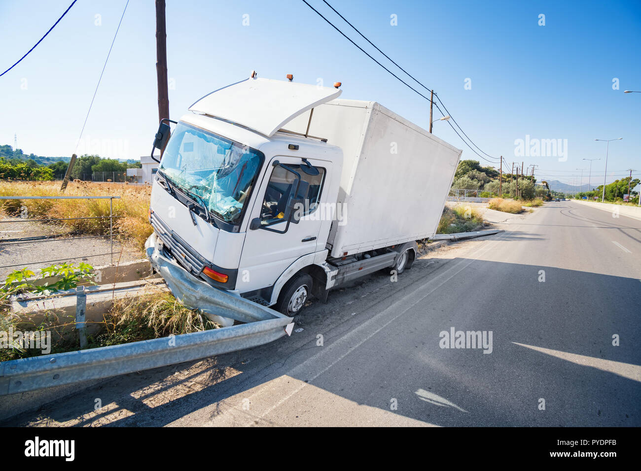 Crashed truck that hit crashed barrier on road, broken windshield, sunny day Stock Photo